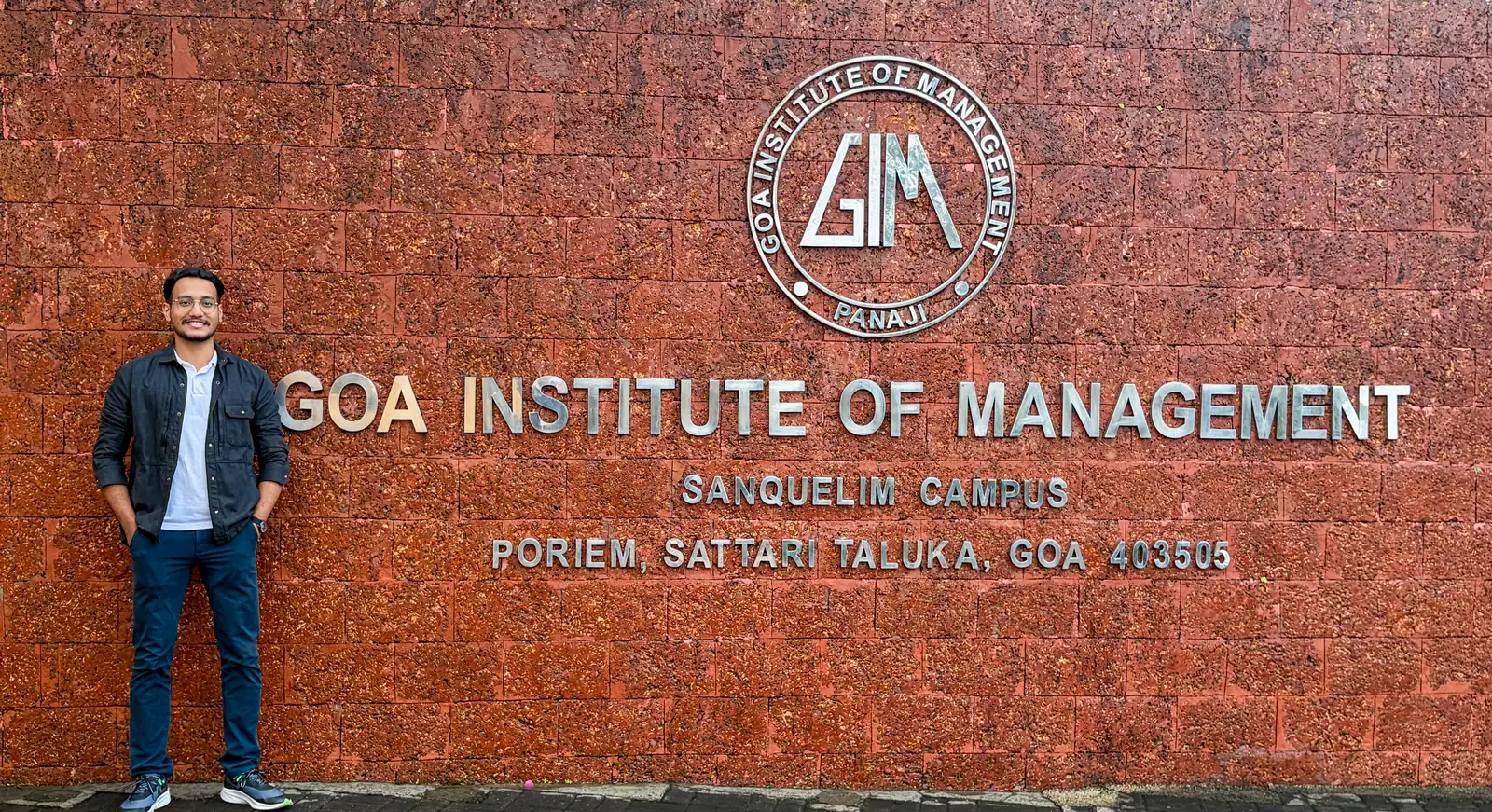 Milind Gauns beside the Goa Institute of Management campus sign